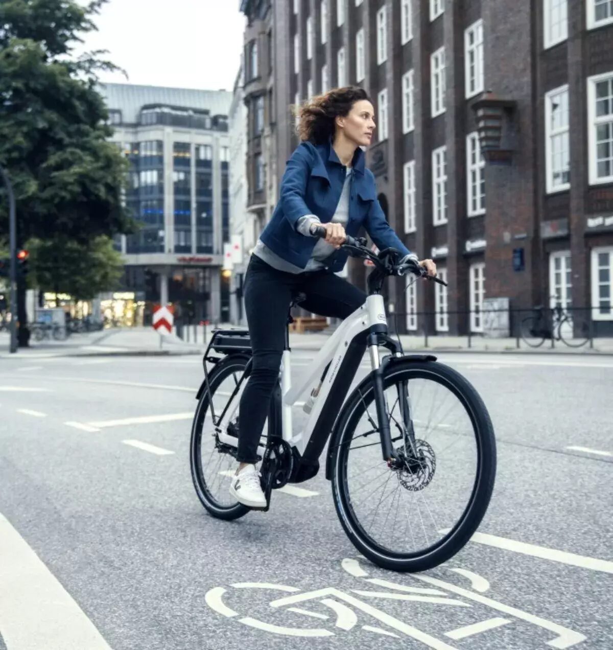 Vrouw fietst op een witte Riese & Muller door de stad